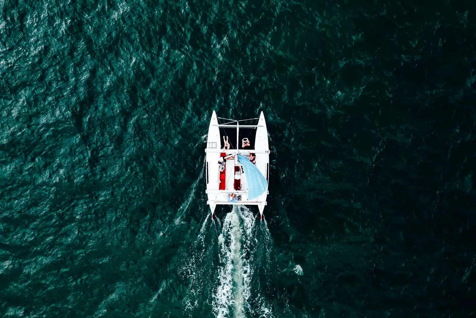 People sitting on a pontoon boat under way on open water on a bright day