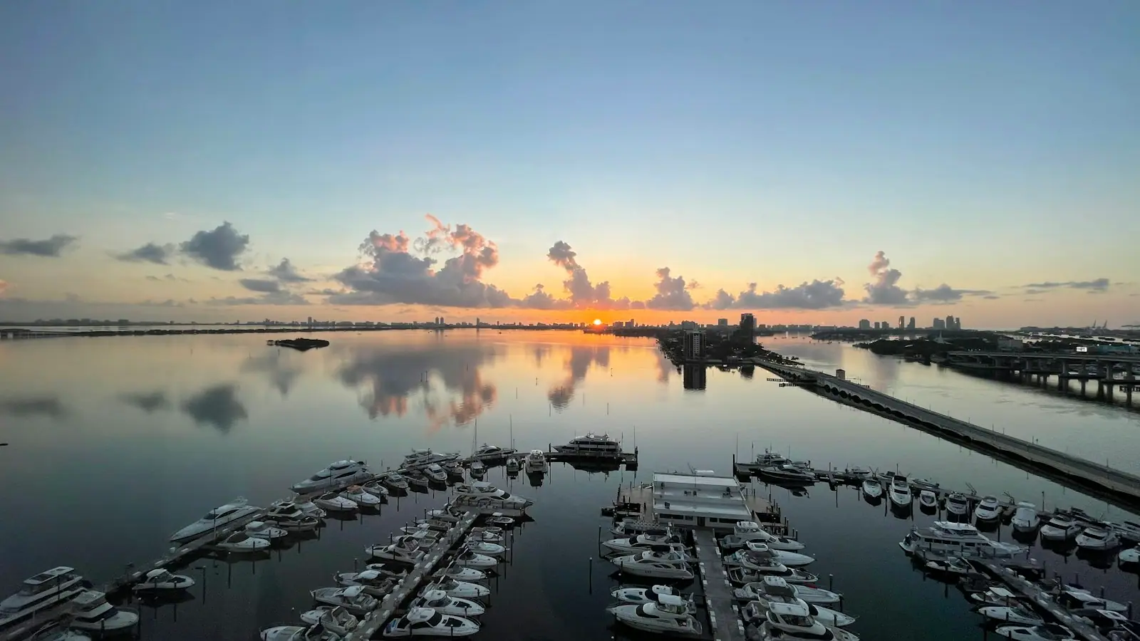 Rows of boats moored in a marina basin on flat water in early morning light
