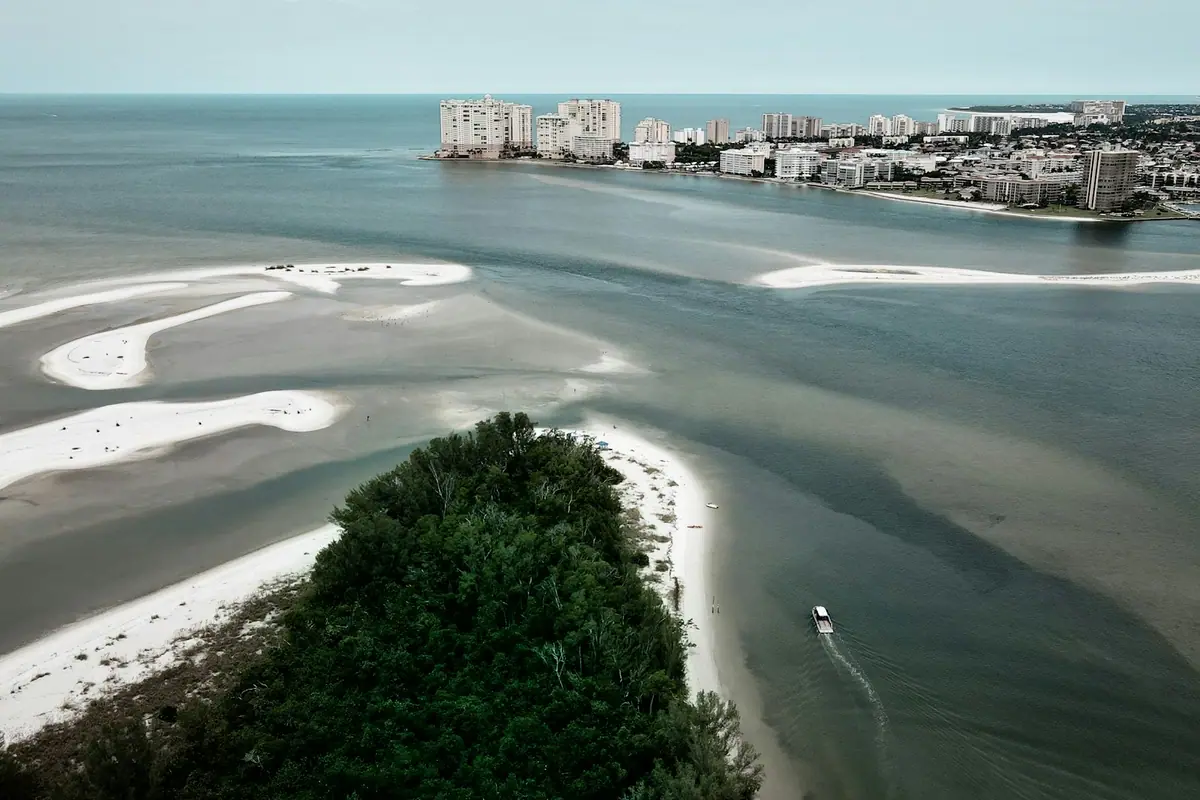 Aerial view of a narrow tidal pass cut between two low sandy shorelines