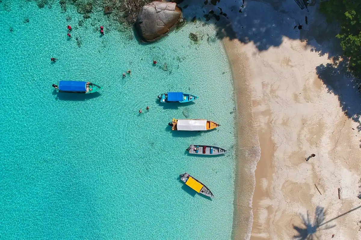 Boats moored on clear shallow water beside a sandbank, seen from above