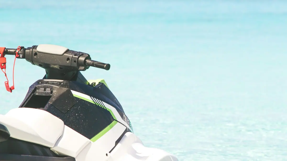 A white and green personal watercraft sitting on flat water