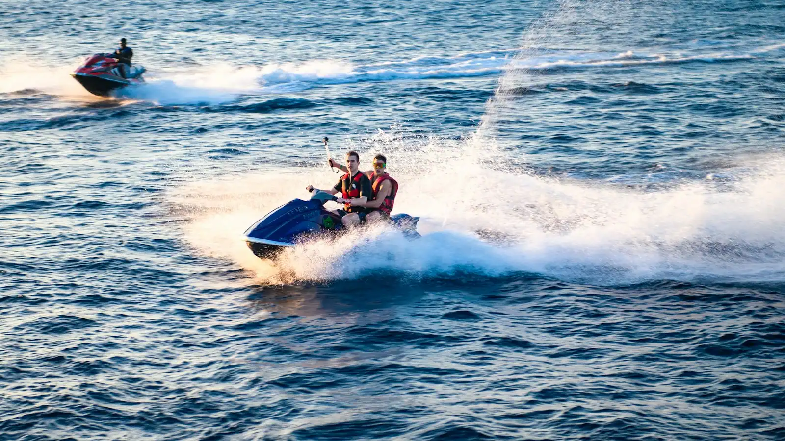 Two riders on a personal watercraft crossing open water