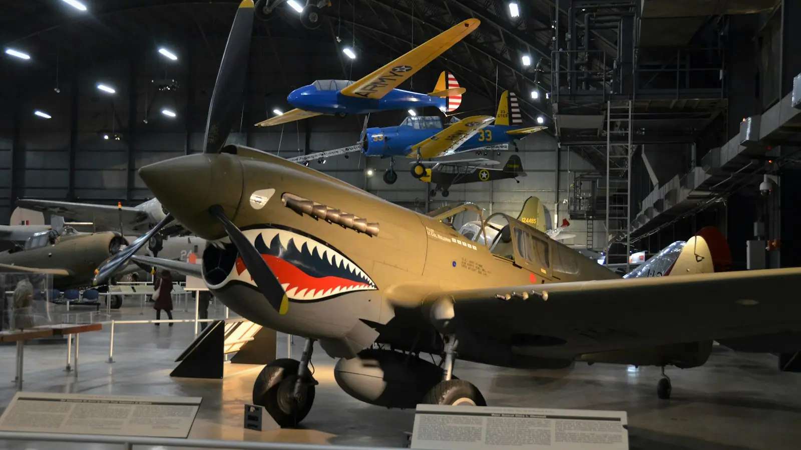 A museum hangar interior with several vintage military aircraft displayed under a high roof