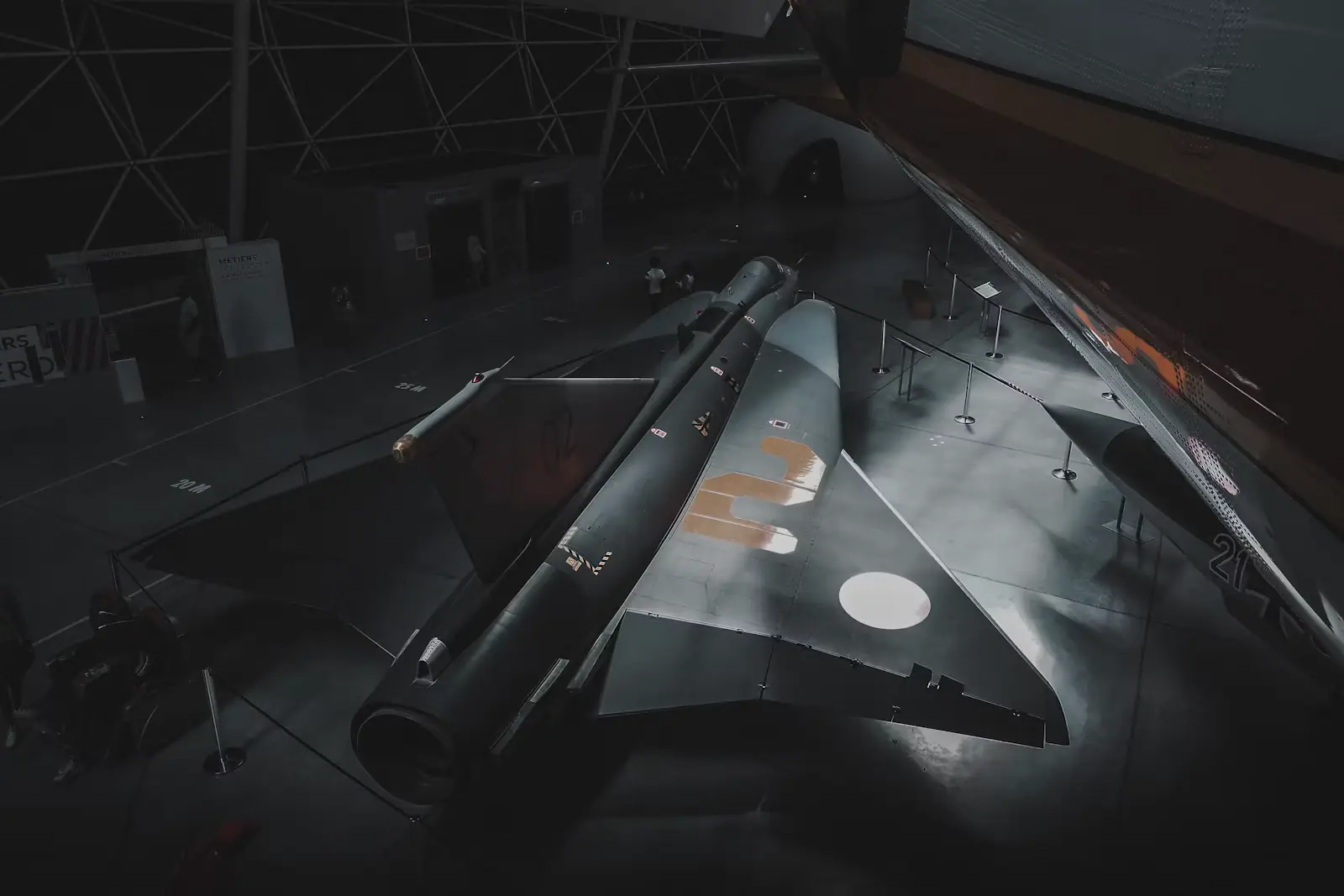 The grey nose and forward fuselage of a military fighter aircraft displayed inside an aviation museum hall