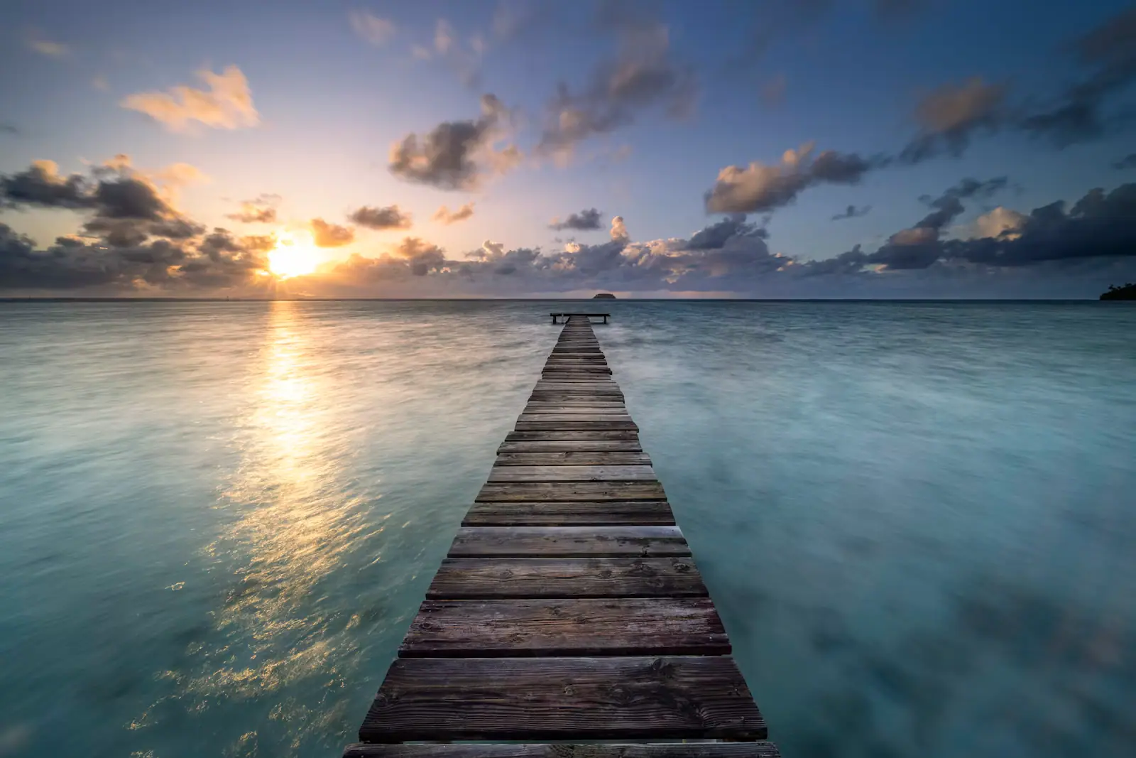 A long timber pier running out over calm water in low evening light