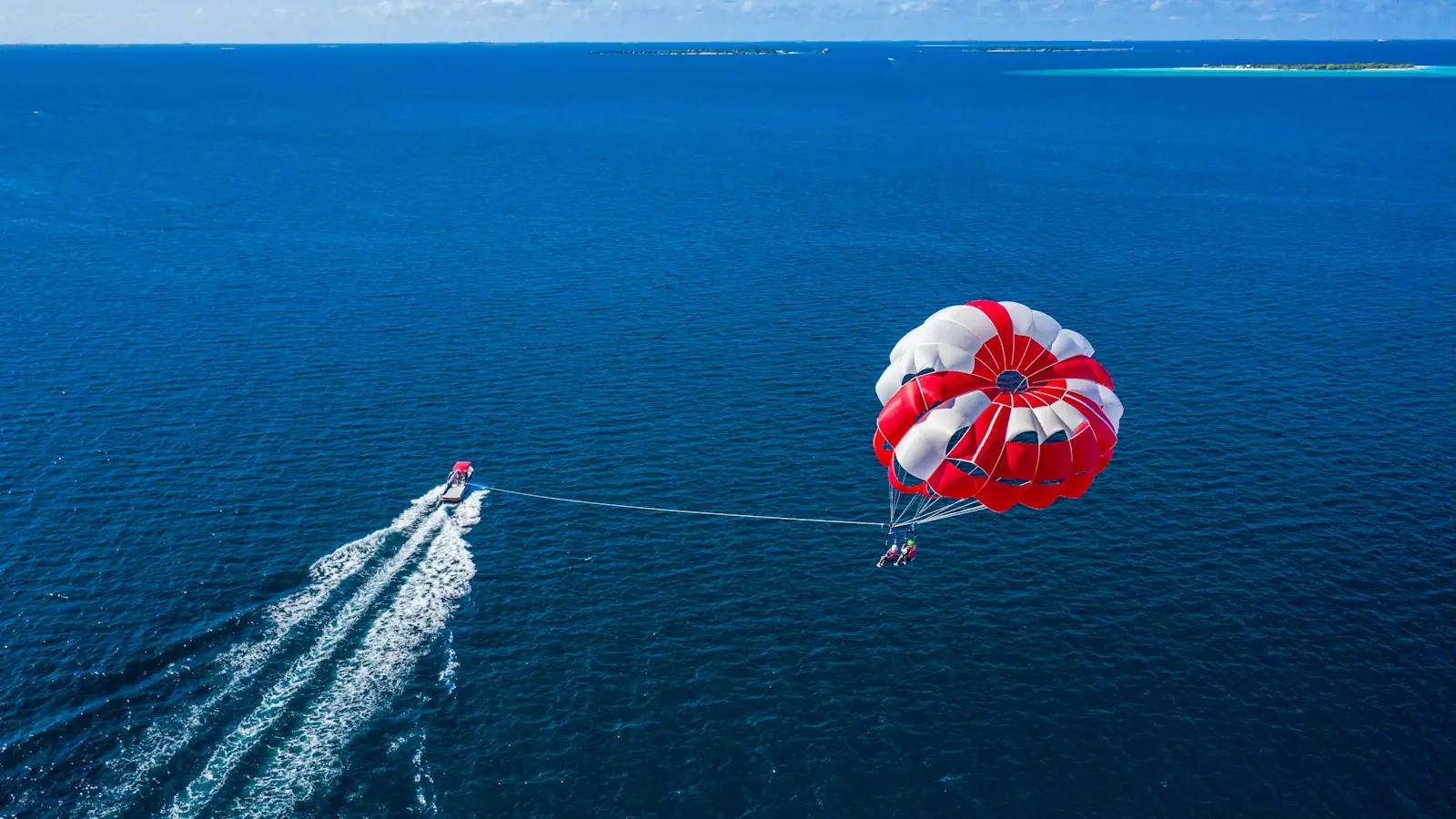 A parasail canopy flying above open water behind a boat