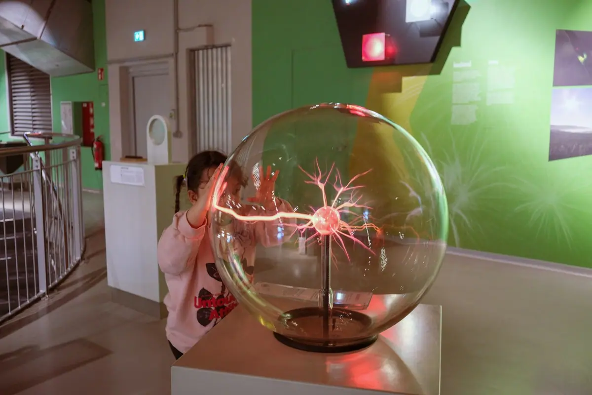 A young person touching a plasma ball exhibit in a science museum